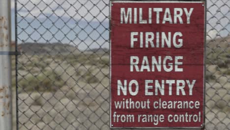 High-quality-3D-CGI-render-of-a-chainlink-fence-at-a-high-security-installation-in-a-desert-scene,-with-a-Military-Firing-Range-No-Entry-sign