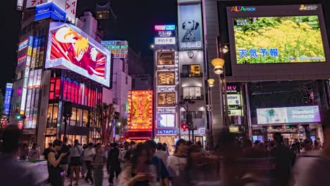 Night-Time-Lapse-of-Crowds,-neon-lights,-many-screens-and-the-3D-LED-screen-billboard-featuring-the-internet-famous-Shinjuku-cat-in-downtown-Shinjuku-Tokyo,-Japan-TILT