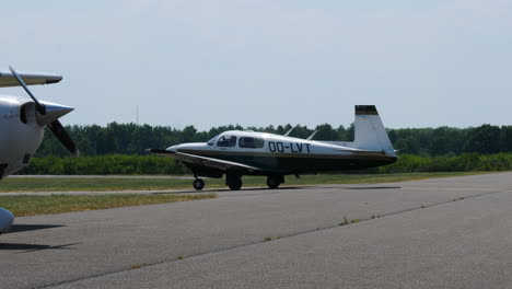 Mooney-M20-aeroplane-taxiing-from-taxiway-to-runway,-hot-summer-day,-airport