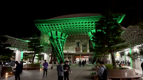 The-Tsuzumi-Gate-at-JR-Kanazawa-Station-East-light-up-green-entrance-with-tourists,-Japan