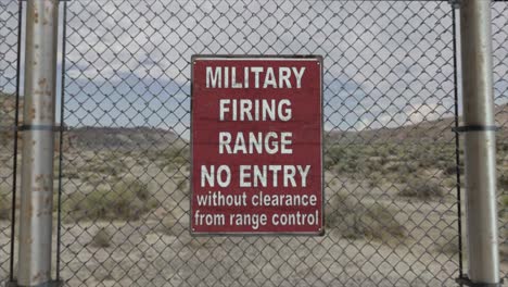 High-quality-3D-CGI-render-with-a-smooth-dollying-in-shot-of-a-chainlink-fence-at-a-high-security-installation-in-a-desert-scene,-with-a-Military-Firing-Range-No-Entry-sign