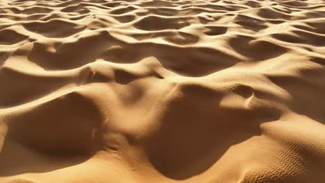 Die-Drohne-Fliegt-Vorwärts-Und-Abwärts-Und-Blickt-Auf-Den-Sand-Der-Sahara-Wüste,-Während-Der-Wind-Sand-über-Die-Dünen-In-Tunesien-Bläst.-Luftaufnahmen-In-4K