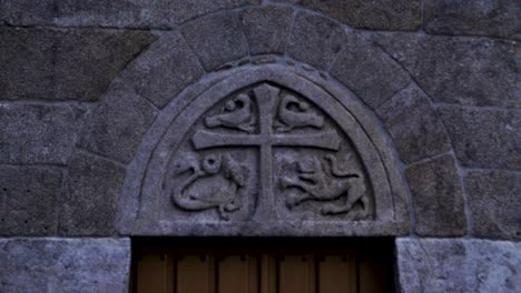Carved-stone-detail-of-cross-and-snake-lion-and-fish-animals-in-old-church