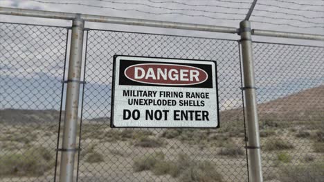 High-quality-3D-CGI-render-with-a-smooth-dollying-out-shot-of-a-chainlink-fence-at-a-high-security-installation-in-a-desert-scene,-with-a-Danger-Military-Firing-Range-sign