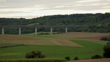 High-speed-ICE-train-crossing-a-bridge-in-a-rural-landscape-at-dusk