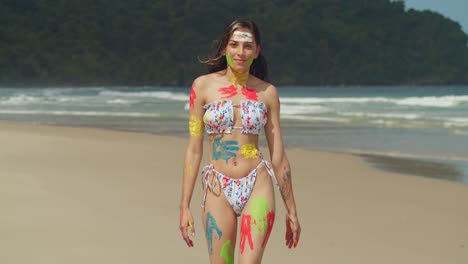 On-a-sunny-day-in-the-Caribbean,-a-girl-adorned-in-body-paint-and-a-bikini-walks-along-a-white-sand-beach
