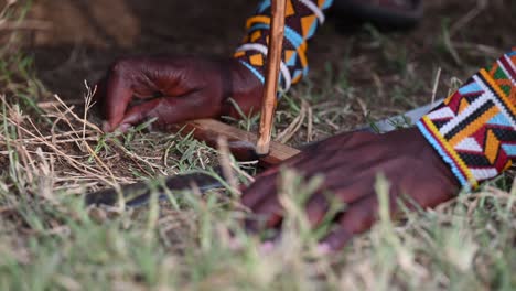 Massai-Männer-Nutzen-Die-Bogenbohrtechnik,-Um-Im-Massai-Dorf-In-Kenia-Ein-Feuer-Zu-Entfachen
