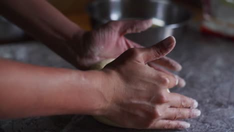 freshly-mixed-ball-of-dough-being-kneaded-by-hand-on-marble-tabletop,-filmed-as-closeup-slow-motion-shot