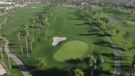 Heritage-Palms-Golf-Course-in-Indio,-California-with-drone-video-pull-back-from-green-close-up