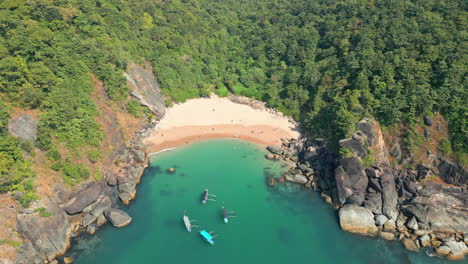 -Aerial-view-of-secret-Butterfly-beach-with-rocky-bay-and-fishing-boats-Goa-India
