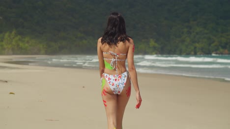 Disfrutando-Del-Calor-Del-Sol-Caribeño,-Una-Chica-En-Bikini-Y-Pintura-Corporal-Caminando-Por-Una-Playa-De-Arena-Blanca