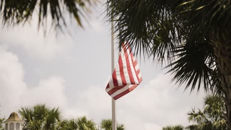 Bandera-De-Estados-Unidos-Ondeando-Al-Viento-En-Cámara-Lenta-Con-Un-Cielo-Brillante-Y-árboles-Tropicales