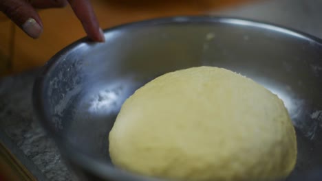 Finger-sliding-over-the-rim-of-bowl-with-raised-dough-ball-inside,-filmed-as-close-up-slow-motion-shot