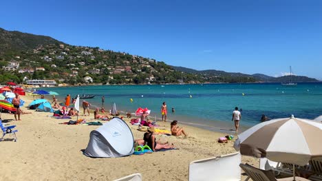 Tourists-and-locals-enjoying-a-beautiful-fun-sunny-summer-beach-day-with-turquoise-sea-water-and-blue-sky-in-Saint-Clair-South-of-France,-holiday-vacation-activity,-4K-static-shot