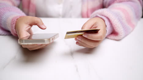 Die-Hand-Einer-Nahaufnahme-Hält-Ein-Smartphone-Und-Nutzt-Eine-Nachgebildete-Bankkreditkarte-Für-Online-Einkaufsdienste,-Um-Geld-Mit-Bargeldloser-Technologie-Zu-Bezahlen