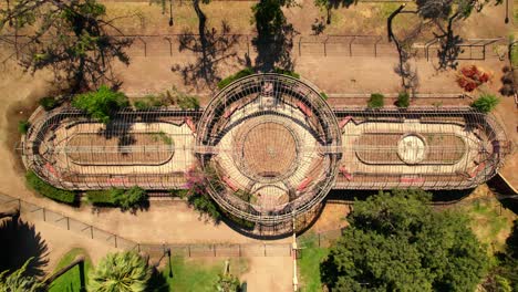 Top-view-descending-over-the-abandoned-Quinta-Normal-Greenhouse-on-a-sunny-day,-Santiago,-Chile