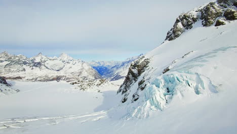 Drone-advances-through-a-snow-kissed-mountain-expanse,-revealing-majestic-peaks-as-a-breathtaking-backdrop