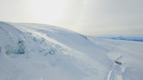 Unberührte-Schneebedeckte-Landschaften-In-Der-Schweiz,-Wo-Die-Drohne-Die-Pure-Schönheit-Der-Weißen-Weite-Einfängt-Und-Mit-Einigen-Skifahrern-In-Der-Ferne-Ein-Winterwunderland-Spektakel-Schafft