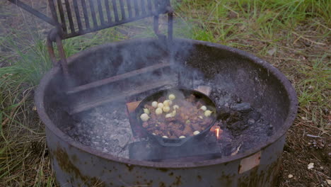 Campingmahlzeit-Aus-Fleisch-Und-Zwiebeln-In-Gusseisen-über-Dem-Lagerfeuer-Kochen