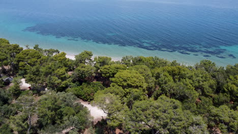 Eine-Drohne-Taucht-An-Einem-Wald-Vorbei-Und-Gibt-Den-Blick-Auf-Den-Strand-In-Griechenland-Frei
