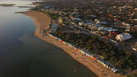 Drone-footage-overlooking-Brighton's-colourful-bathing-boxes-in-Melbourne,-Australia