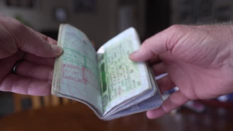 Man-looking-through-his-passport-pages-full-of-travel-stamps-and-visas