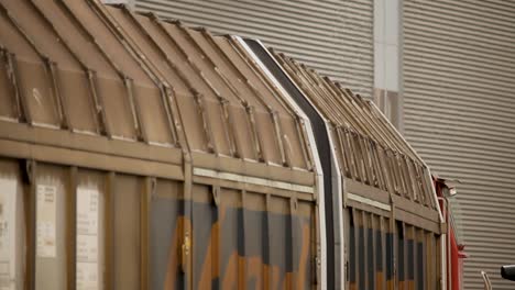 Seitenansicht-Eines-Fahrenden-Rostigen-Eisenbahnwaggons-Mit-Fokus-Auf-Die-Dachkonstruktion