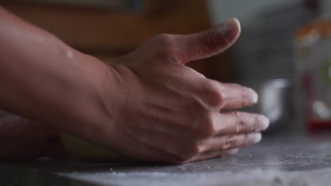 Ball-of-dough-gently-rounded-into-ball-shape-by-hand-on-granite-tabletop,-filmed-as-close-up-shot