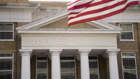 Manatee-County-Clerk-Des-Bezirksgerichts-Mit-Der-US-Flagge,-Die-In-Zeitlupe-Flattert