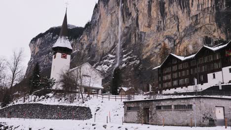 Panning-shot-of-the-Staubbach-falls-in-Lauterbrunnen-with-the-church-and-river-in-the-foreground