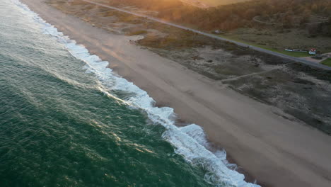 Scenic-Shot-Tilt-Up-Sunset-Waves-Beach-Punta-del-Este-Uruguay,-Coastline-Campaign-Haze-Road