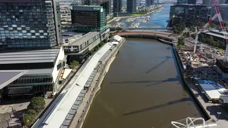 Aerial-footage-along-the-Yarra-River-and-DFO-South-Wharf,-where-direct-factory-outlets-chain-are-housed