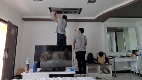 Eine-Aufnahme-Von-Zwei-Fleißigen-Männern,-Die-Tagsüber-Die-Klimaanlage-In-Einem-Hotelzimmer-Reparieren