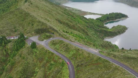 Drone-view-of-winding-road-and-Lagoa-Do-Fogo-during-cloudy-day,-Azores