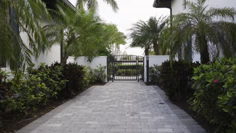 Tropical-walkway-in-a-gated-community-with-palm-trees-on-a-sunny-day,-with-gate-closed