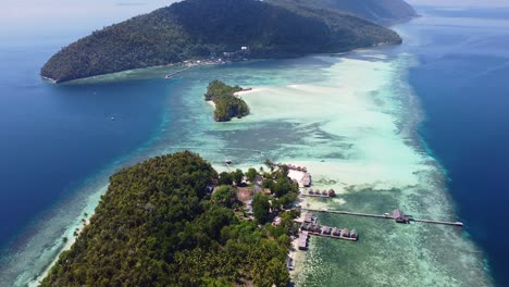 Malerische-Luftaufnahme-Einfacher-Strandhütten-Mit-Blick-Auf-Kristallklares-Meerwasser-Mit-Korallenriffen-Im-Beliebten-Tauchziel-Raja-Ampat,-West-Papua,-Indonesien