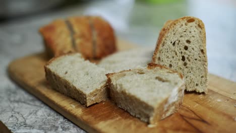 Freshly-cut-bread-loaf-presented-on-wooden-cutting-board,-filmed-as-closeup-handheld-slow-motion-shot