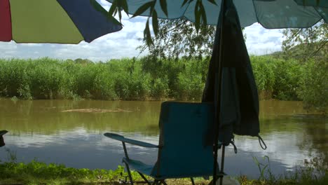 A-chair-and-umbrella-by-the-river-at-a-fishing-session-on-a-sunny-day