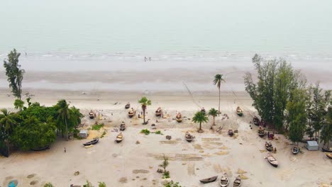 Aerial-view-of-a-tropical-beach-scattered-with-boats-and-palm-trees