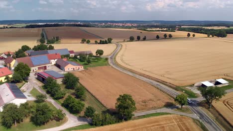 Aerial-Tracking-Shot-of-Car-Driving-Through-Fields-and-Agricultural-Buildings