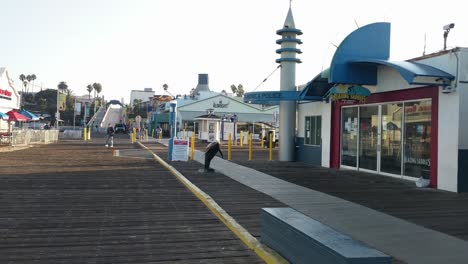 Panning-shot-of-people-walking-along-the-entrance-of-Santa-Monica-pier-in-Los-Angeles-after-reopening-from-Covid-19