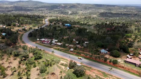 High-aerial-view-over-a-small-village-and-palm-trees-next-to-the-Mombasa-road