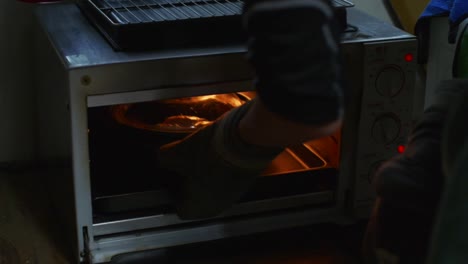 Baking-pot-with-lid-pushed-into-oven-and-closed-inside,-filmed-as-medium-closeup-shot-in-slow-motion