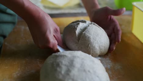 Fully-prepared-dough-ball-ready-for-baking-lifted-up-using-scraping-tool,-filmed-as-close-up-in-slow-motion-style