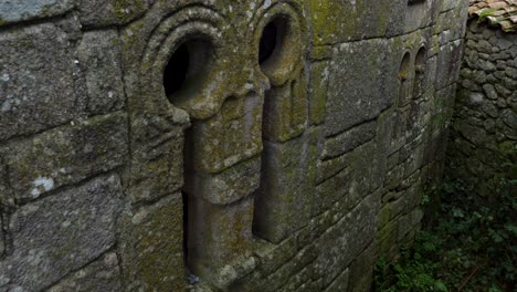 Kunstvoll-Geschnitzter-Archäologischer-Überrest-An-Der-Seite-Der-Kirche-In-Spanien,-Moosiger-Felsen