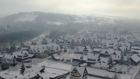 Idyllic-wintry-aerial-panorama-of-mountain-village-houses-in-snow-and-hazy-sunlight