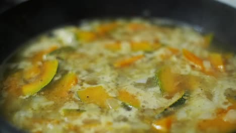 Delicious-pumpkin-soup-put-to-boil-in-black-frying-pan,-filmed-as-closeup-slow-motion-shot-in-handheld-style