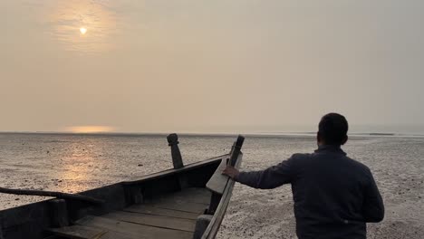 Nahaufnahme-Eines-Mannes,-Der-Während-Des-Sonnenuntergangs-An-Einem-Strand-In-Bengalen,-Indien,-Ein-Indisches-Fischerboot-Hält