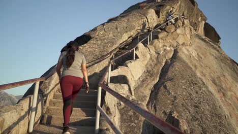 Cinematic-gimbal-shot-of-tourist-climbing-to-the-peak-of-Moro-Rock-in-California's-Sequoia-National-Forest-during-sunset