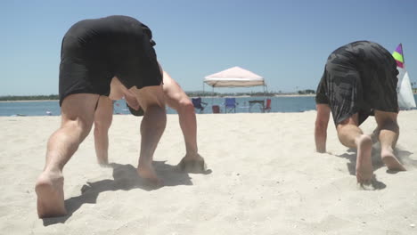 Male-athletes-doing-bear-crawl-exercise-on-the-beach-with-pacific-ocean-in-background